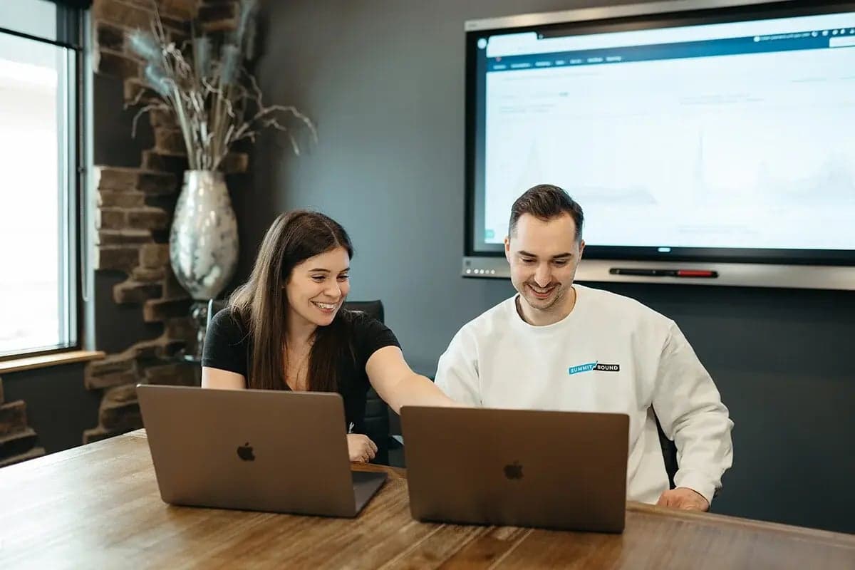 Two team members reviewing a HubSpot dashboard together on laptops